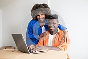 Happy Black Family Couple Using Laptop Together While Moving To New Home