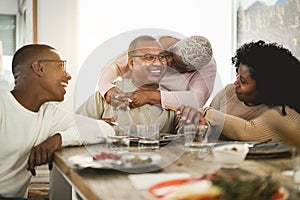 Happy black family eating lunch at home - Main focus on father face