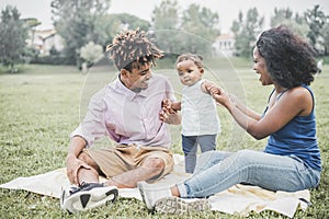 Happy black family having fun doing picnic outdoor - Parents and their daughter enjoying time together in a weekend day - Love