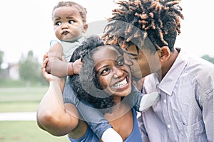 Happy black family having fun in a park outdoor - Mother and father with their daughter enjoying time together in a weekend day