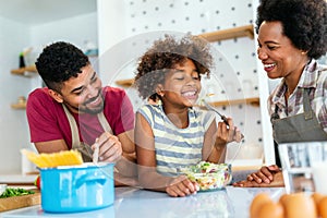 Happy black family in the kitchen having fun and cooking together. Healthy food at home.