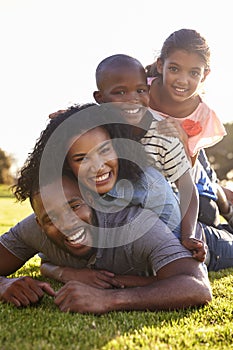 Happy black family lying in a pile on grass outdoors