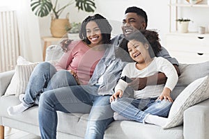 Happy black family relaxing and at home, watching tv together