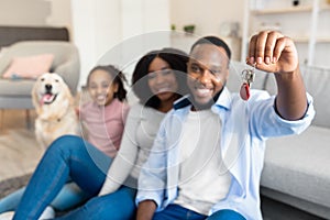 Happy black family showing keys of their new apartment