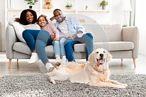 Happy black family sitting in living room with dog