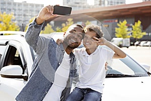 Happy black family taking selfie with brand new car