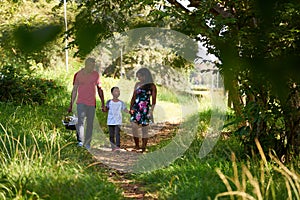 Happy Black Family Walking In City Park With Picnic Basket photo