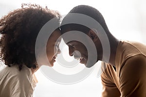 Happy black father and cute mixed-race kid daughter touching foreheads