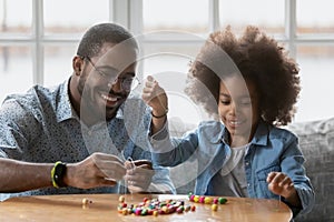 Happy Black father and daughter girl making decoration together