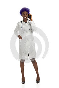 Happy black female doctor is standing and talking on the telephone. Front view, full length, isolated