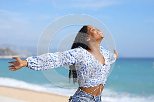 Happy black female outstretching arms on the beach