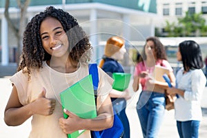 Happy black female student with group of latin american and caucasian young adults