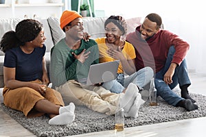 Happy black friends men and women using laptop, home interior