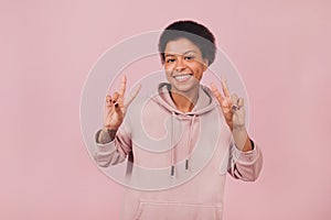 Happy black girl posing with peace gesture on pink background