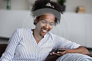 Happy Black girl, young woman relaxing on sofa