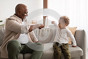 Happy Black Grandpa And Little Grandson Bumping Fists At Home