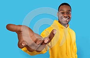Happy black guy showing big outstretched hand, offering help, taking or giving something, reaching out for support