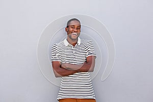 Happy black guy smiling with arms crossed against gray wall