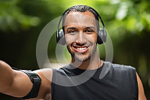 Happy black guy taking selfie while exercising at park