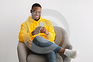Happy Black Guy Using New Application On Smartphone, Gray Background