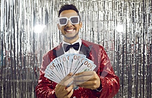 Happy black guy who has won lots of money holding bunch of banknotes and smiling