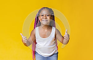 Happy black little girl with afro-braids showing thumbs up