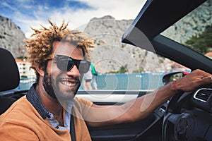 Happy black man driving a convertible car.