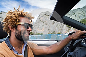 Happy black man driving a convertible car.