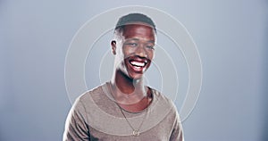 Happy black man, face and laugh in studio for funny meme, cheerful expression or emoji on grey background. Portrait