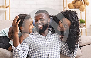 Happy black man laughing with wife and daughter at home