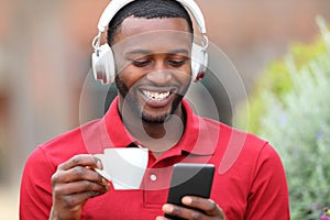 Happy black man listening to music drinking coffee