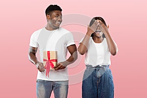 Happy black man making surprise for his woman giving box