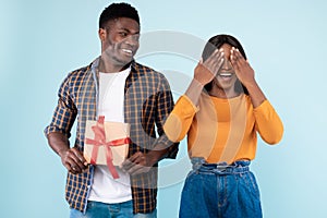 Happy black man making surprise for his woman giving box