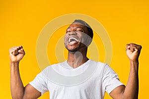 Happy Black Man Screaming And Shaking Fists Over Yellow Background