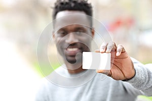 Happy black man showing blank credit card in the park photo