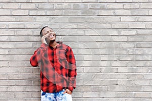 Happy black man talking on cell phone by wall