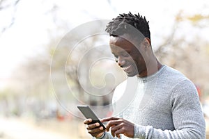 Happy black man using smart phone in a park