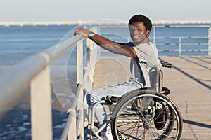 Happy Black man in wheelchair enjoying walking at seafront photo