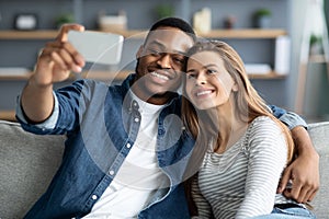 Happy Black Man And White Woman Taking Selfie On Smartphone At Home