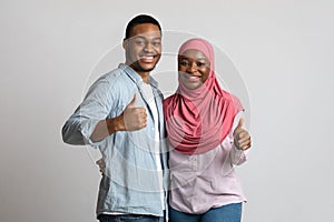 Happy black man and woman hugging and showing thumbs up