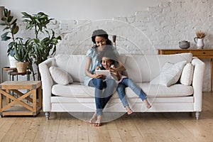 Happy Black mom and cheerful preschool daughter girl reading book