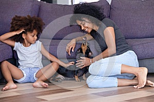 Happy black mom and daughter relax having fun with dog photo