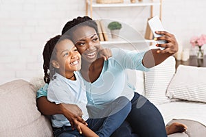 Happy black mom and daughter taking selfie