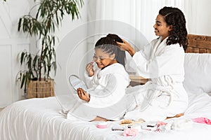 Happy Black Mom Her Daughter In Bathrobes Playing Beauty Salon At Home