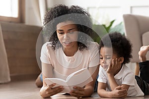 Happy black mom reading fairy tales to cute son.