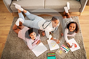 Happy Black Mother And Daughters Drawing Lying On Floor Indoors