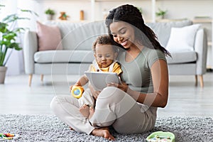 Happy Black Mother And Toddler Child Relaxing With Digital Tablet At Home