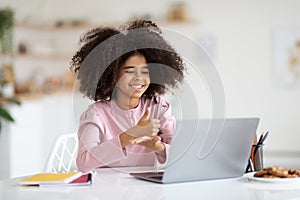 Happy black schooler looking at laptop screen, showing thumb up