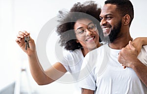 Happy Black Spouses Holding New House Key Embracing At Home
