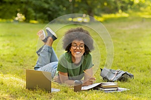 Happy black student girl preparring for exams outdoors with laptop and coffee